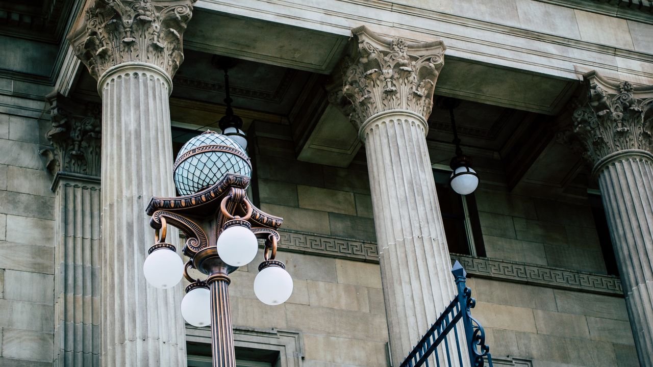 An elegant view of classic architectural columns with an antique street lamp, ideal for urban landscapes.
