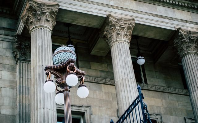 An elegant view of classic architectural columns with an antique street lamp, ideal for urban landscapes.