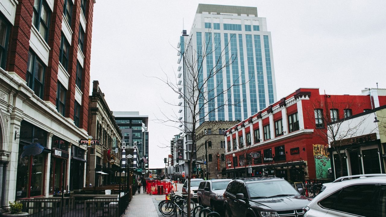 Busy urban street lined with shops and a towering skyscraper, showcasing city life.