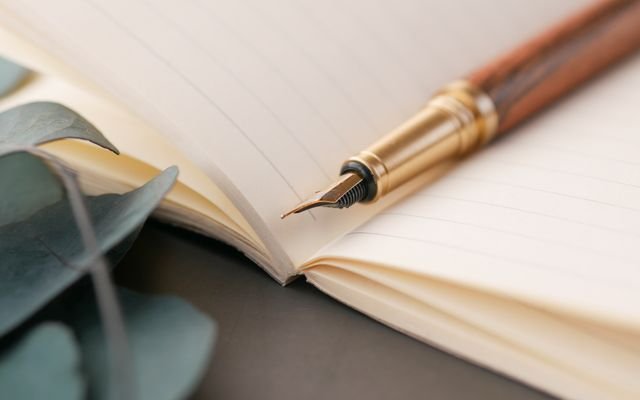 A closeup of a luxurious fountain pen resting on a lined notebook, perfect for writing enthusiasts.