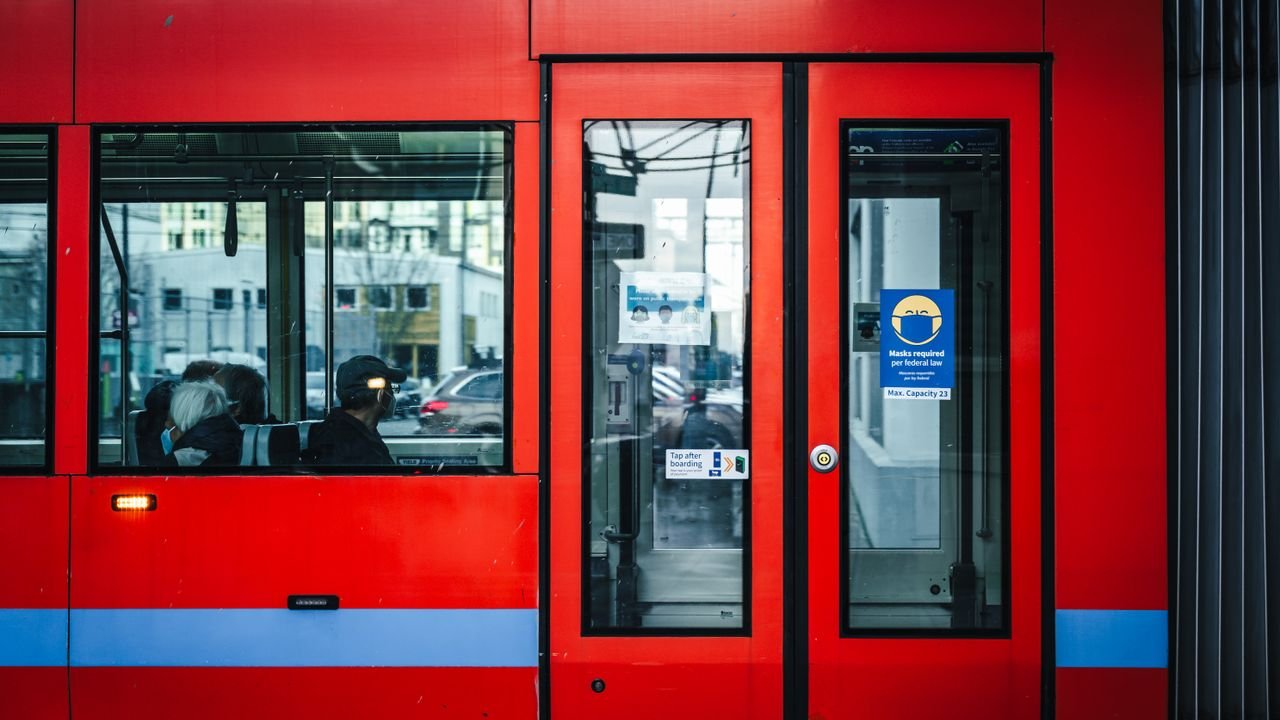 Side view of a red tram with commuters in an urban setting