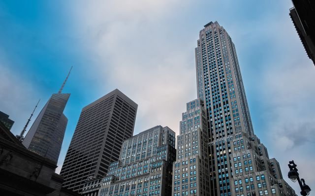 Low angle view of modern skyscrapers against a blue sky in a bustling urban district, showcasing architectural elegance.