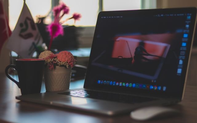 A modern workspace featuring a laptop, coffee cup, and decorative elements on a desk, ideal for remote work environments.