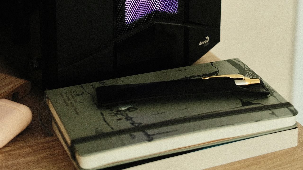 A cozy desk setup in Ukraine featuring a stack of notebooks, a pen, and a warm desk lamp glow.
