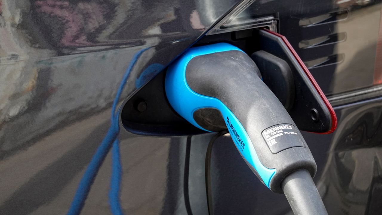 Close-up of an electric vehicle being charged using a Mennekes EV connector.