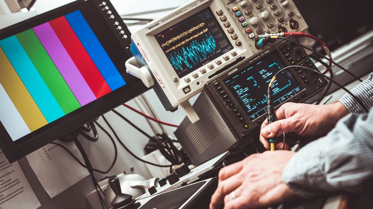 Technician operating laboratory electronic testing and measurement devices with colorful display.