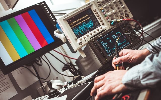 Technician operating laboratory electronic testing and measurement devices with colorful display.