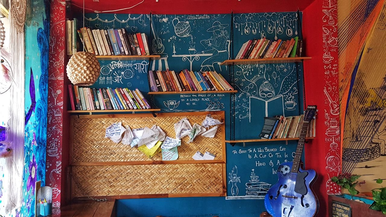 Colorful room with bookshelves, guitar, and artistic decorations creating a cozy atmosphere.
