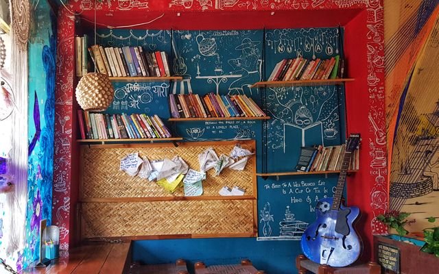 Colorful room with bookshelves, guitar, and artistic decorations creating a cozy atmosphere.