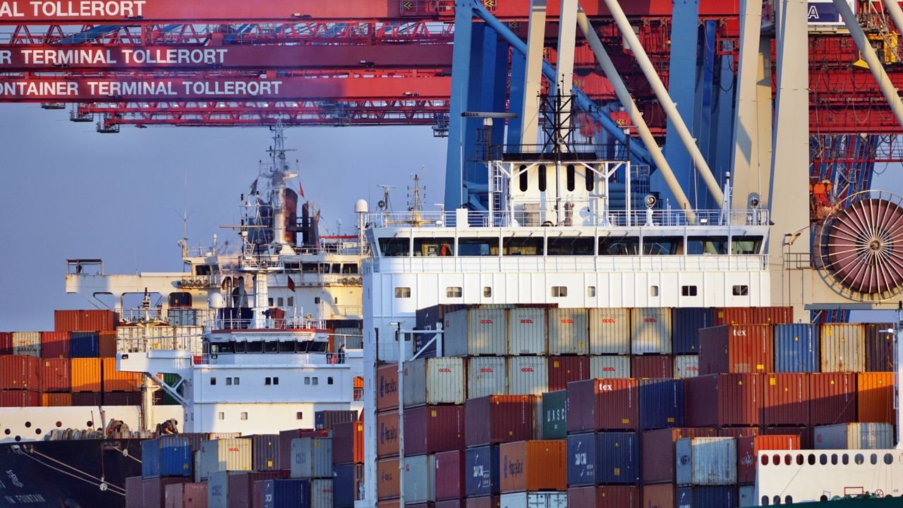 Container ships docked at Tollerort Terminal, Hamburg during sunset.