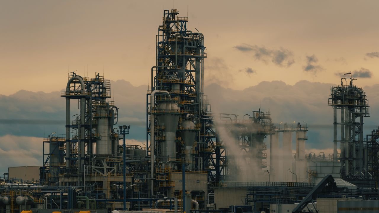 A detailed view of a refinery's towers against a cloudy dusk sky, showcasing industrial architecture.