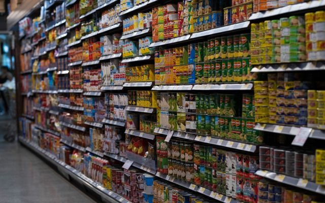 A supermarket aisle filled with various canned goods on shelves, showcasing retail diversity.