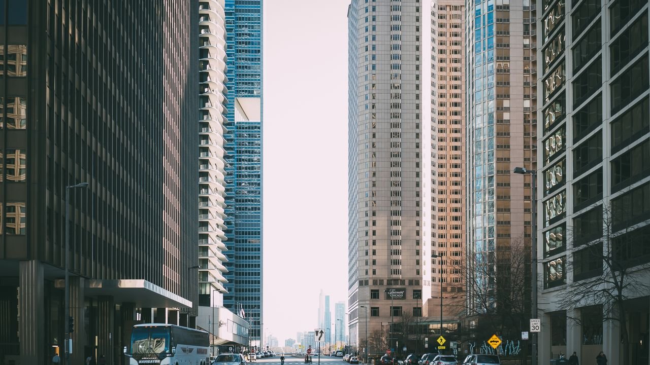 Vibrant city street scene with tall skyscrapers and city life full of cars and pedestrians.