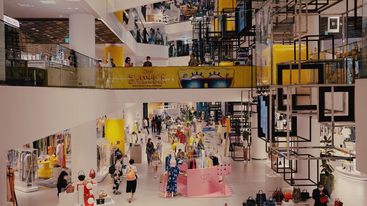 Vibrant mall filled with shoppers, contemporary decor, and stylish fashion outlets.