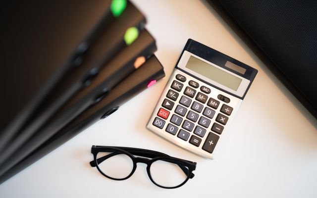 Calculator with glasses and folders on an office desk. Perfect for finance and accounting themes.