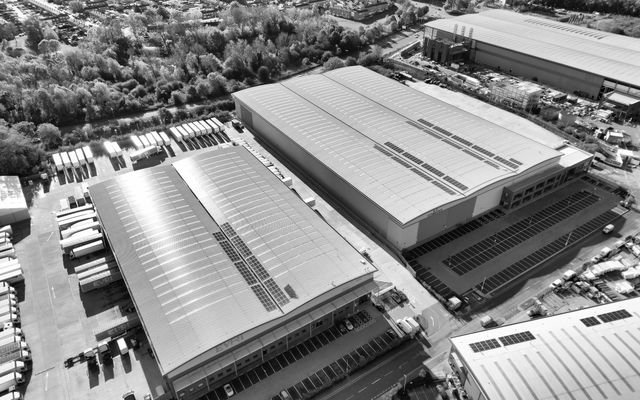 Aerial monochrome image of industrial warehouses and parking spaces in Hertfordshire, UK.