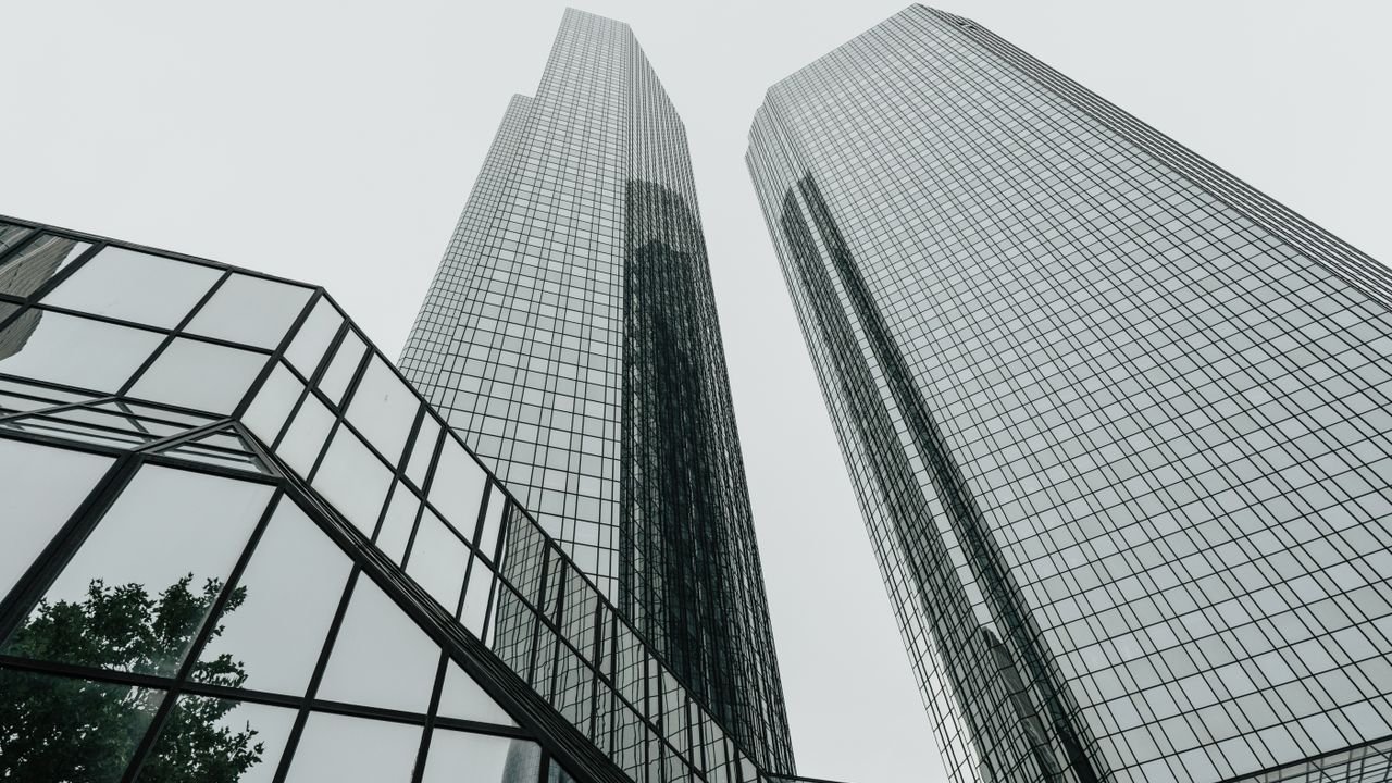 Low-angle view of modern skyscrapers with glass facades in an urban setting, showcasing contemporary architecture.
