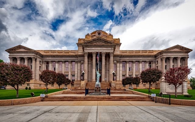 Front view of a neoclassical courthouse building in Colorado with lush greenery.