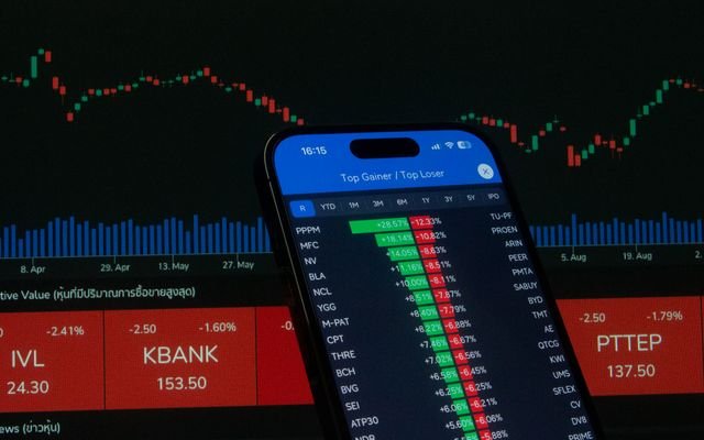Smartphone with stock market data in front of financial chart.