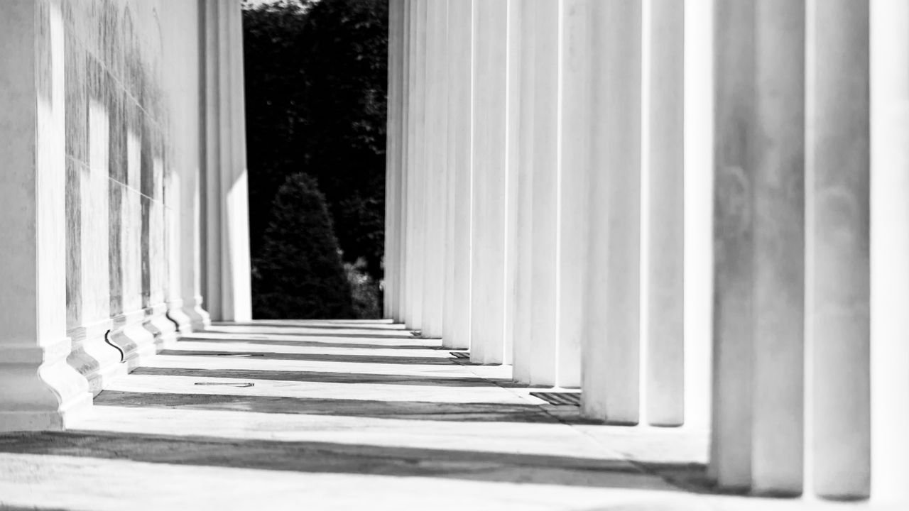Black and white image of elegant columns casting shadows in a Vienna courtyard.