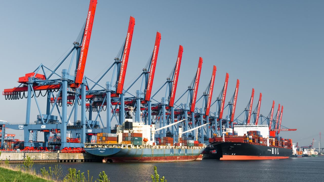 Container ships docked at Hamburg Container Terminal under clear skies, showcasing global trade.