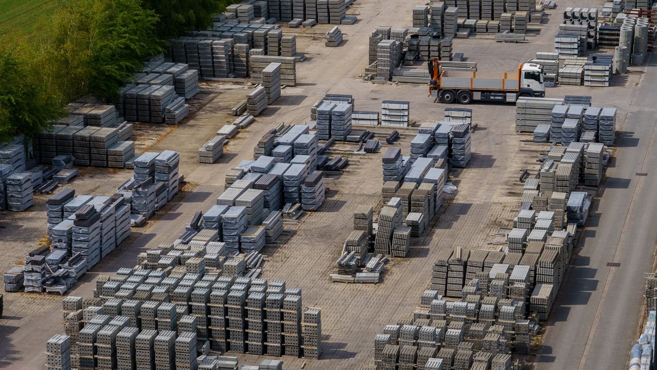 Aerial shot of a vast industrial yard with stacked bricks and a loading truck, captured on a clear day.