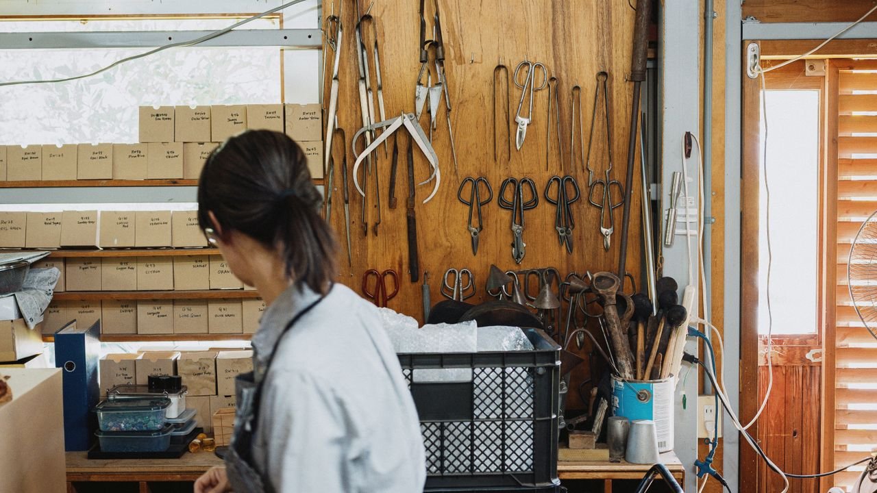 A craftsman working inside a traditional workshop in Nagano, Japan, surrounded by tools and materials.