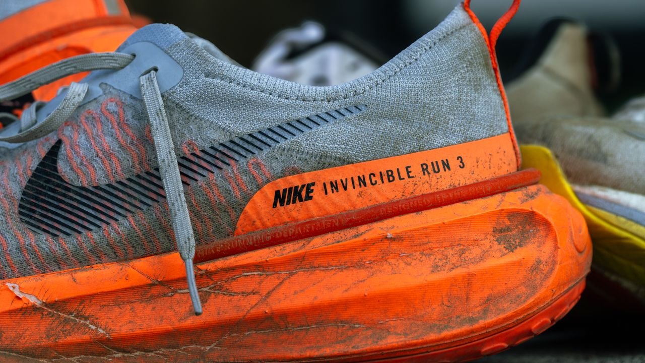 Close-up of worn Nike Invincible Run 3 shoes on concrete, showing wear and tear.