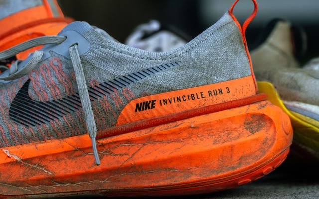 Close-up of worn Nike Invincible Run 3 shoes on concrete, showing wear and tear.