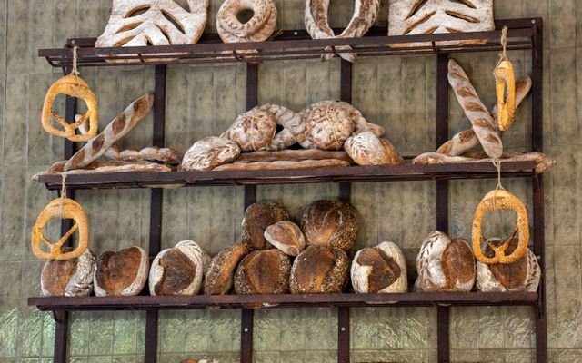 An assortment of artisan bread beautifully arranged on wooden shelves in a Bali bakery.