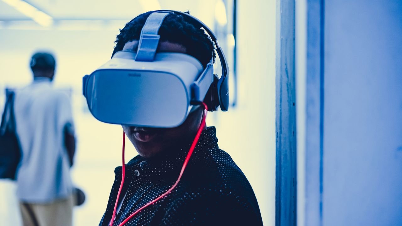 Young adult using a virtual reality headset with headphones in an indoor modern setting.