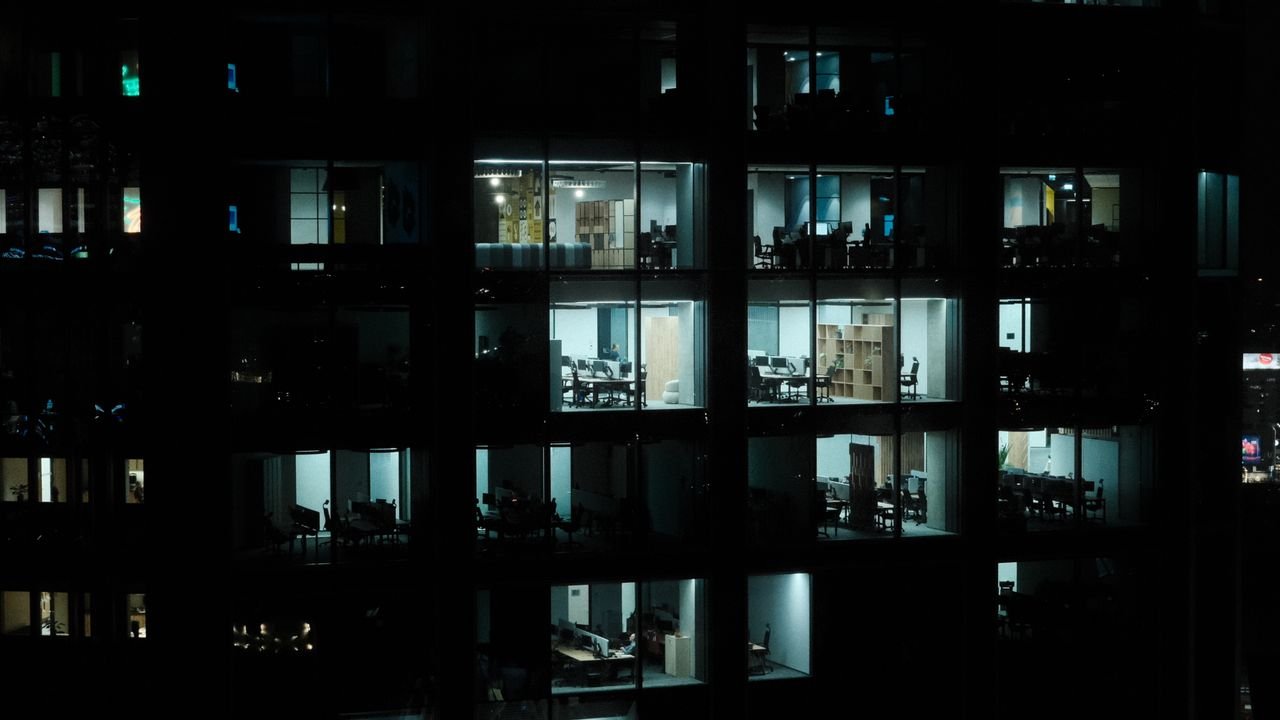 A nighttime view of a modern office building in Warsaw with illuminated interiors.