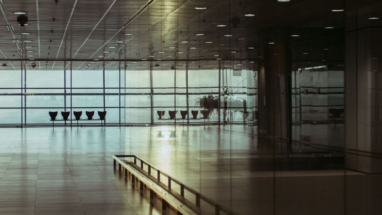 A calm and empty airport terminal in Singapore with a reflective glass facade and soft lighting.