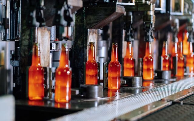 Glass bottles on a production line in a modern glass factory, showcasing industrial automation.