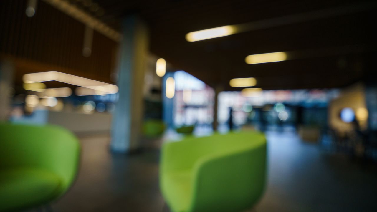 Contemporary office lobby with green chairs and blurred lighting, creating a modern and abstract look.