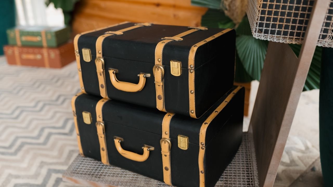 Stacked vintage black suitcases with tan straps create a nostalgic travel vibe.
