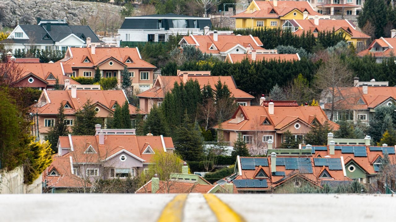 Scenic view of suburban houses with red roofs in Ankara, Türkiye, surrounded by lush greenery and hills.