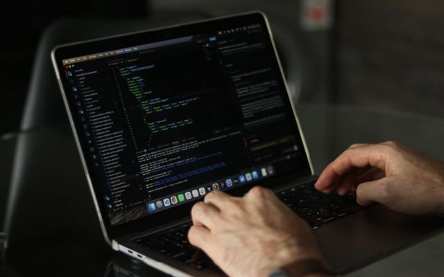 Close-up of hands coding on a laptop, focusing on programming productivity.