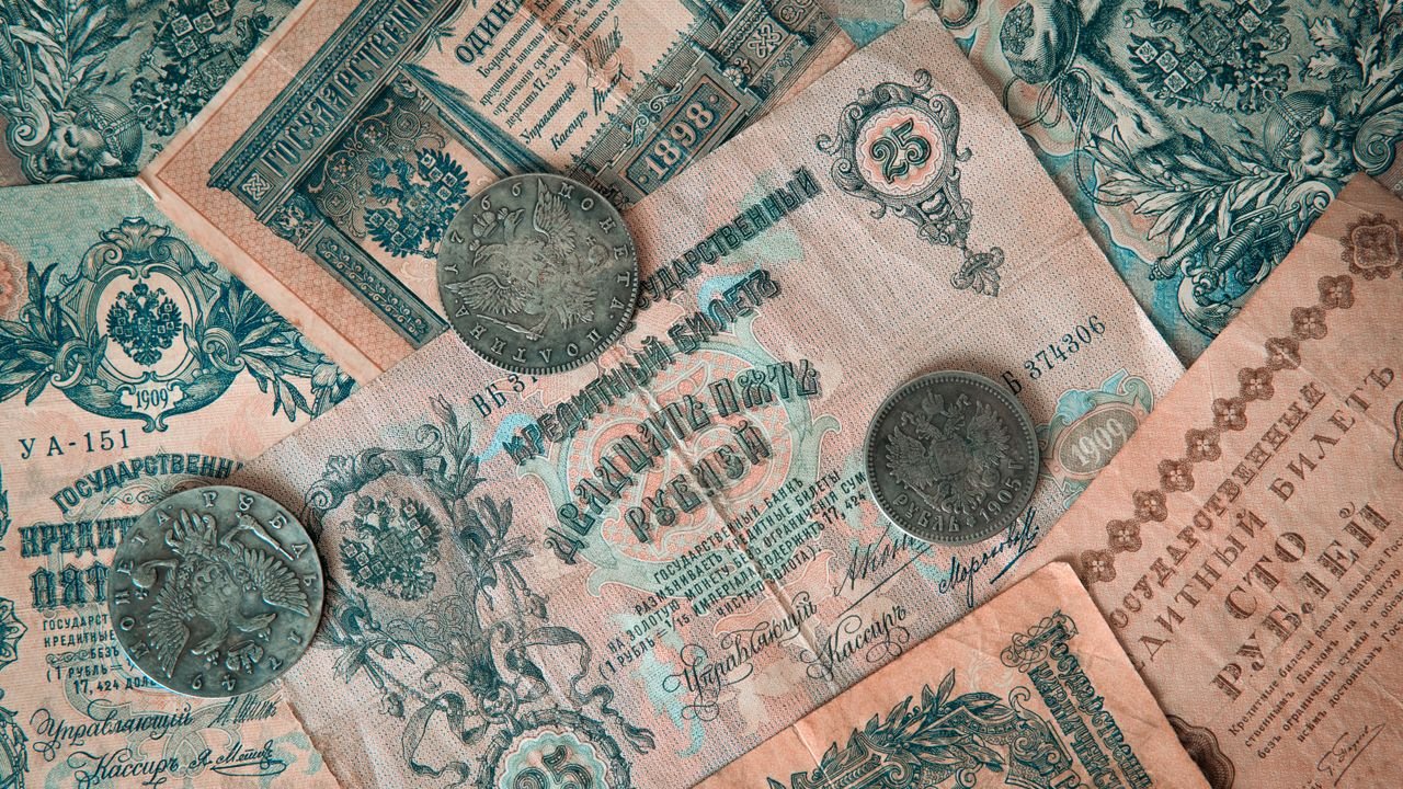 Collection of vintage Russian banknotes and coins featuring intricate designs.