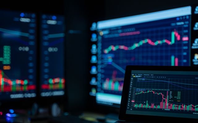 Monitors displaying stock market charts in a dimly lit room, perfect for finance and trading themes.