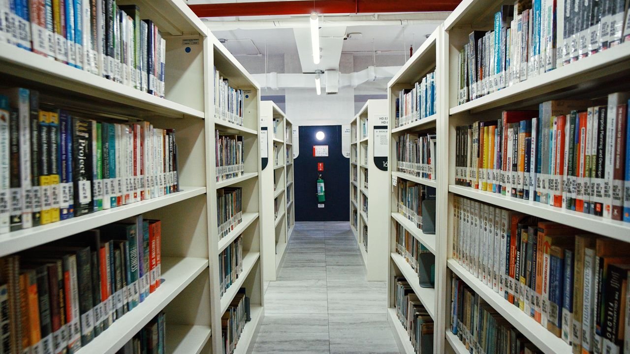 Interior view of a modern library aisle lined with bookshelves under bright lighting.