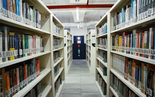 Interior view of a modern library aisle lined with bookshelves under bright lighting.