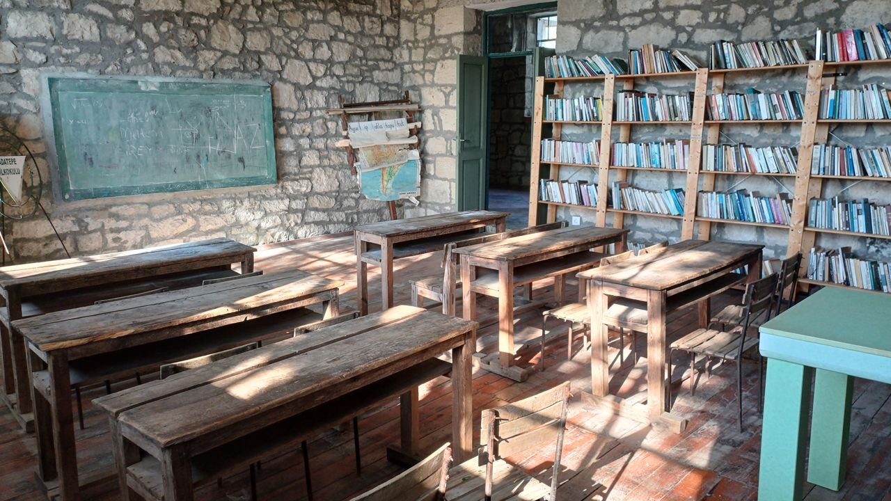 Vintage classroom with wooden desks, blackboard, and bookshelves.