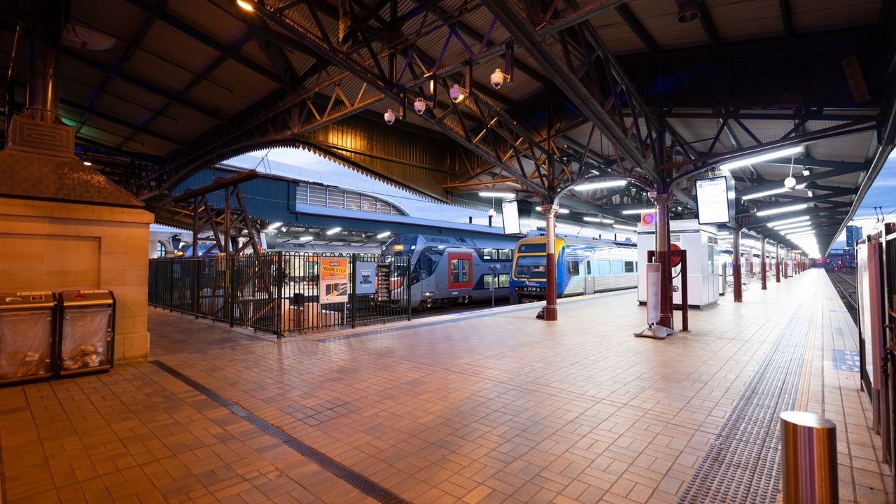 Wide view of Central Railway Station platform in Sydney at dusk with trains and architectural details.