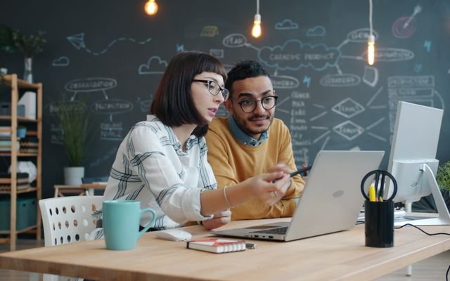 Two coworkers collaborating on a project in a trendy office.