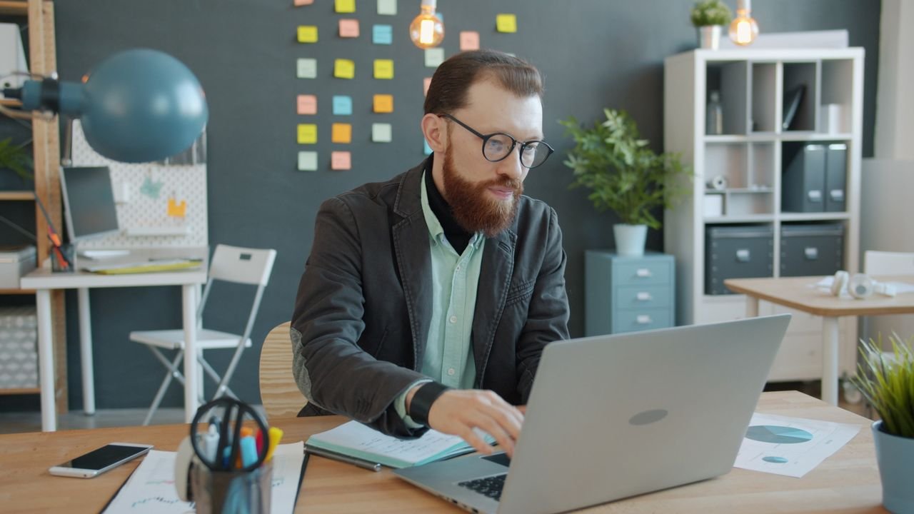 Business professional working diligently on laptop in a modern office space.