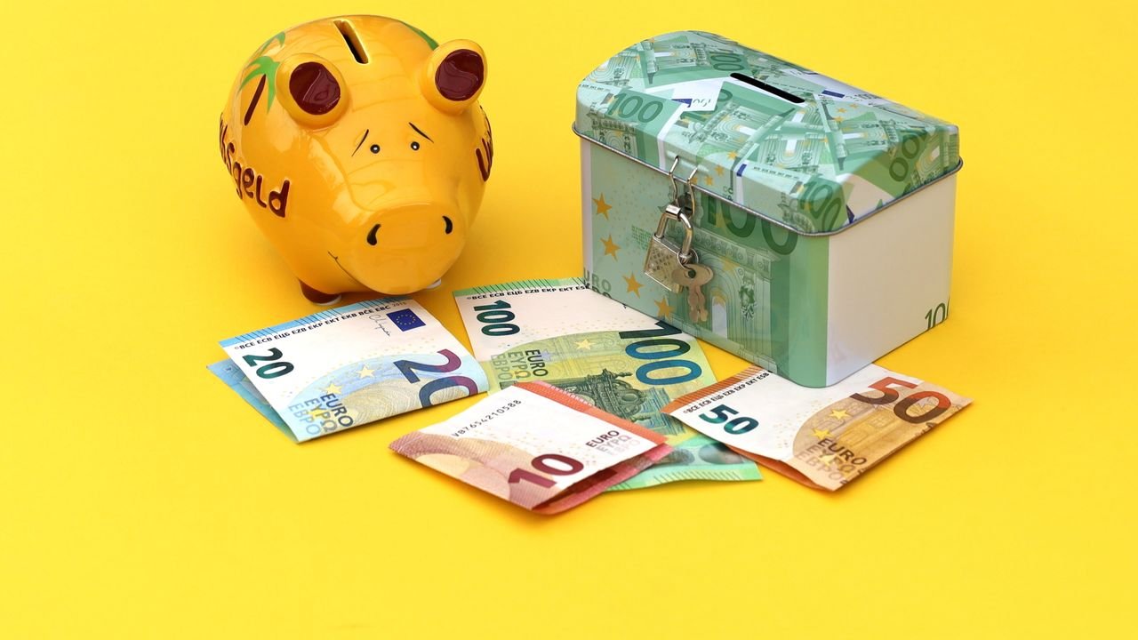 Yellow piggy bank and cash box with Euro notes on bright background.