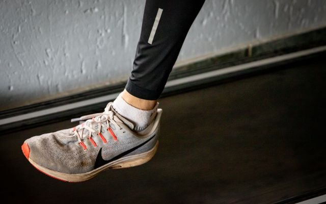 A detailed view of a sneaker mid-stride on a treadmill, showcasing active lifestyle footwear.