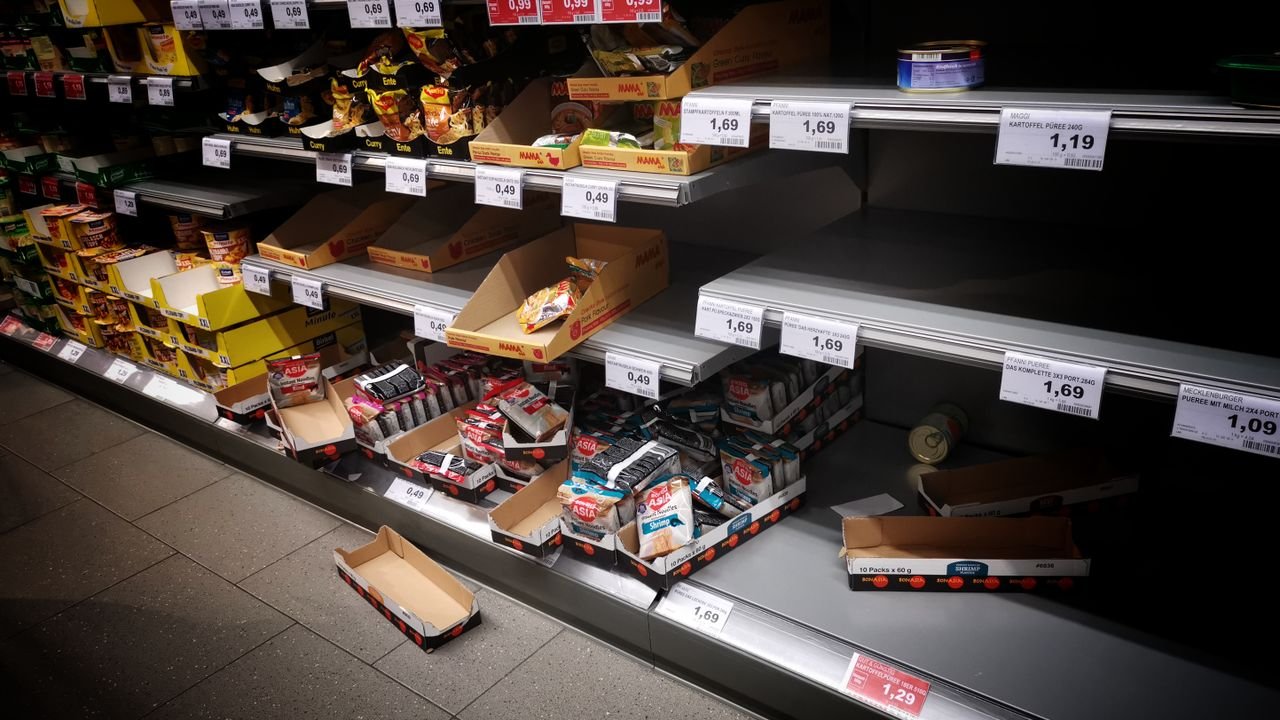 High angle of empty and full shelves in supermarket with price tags and cardboard boxes