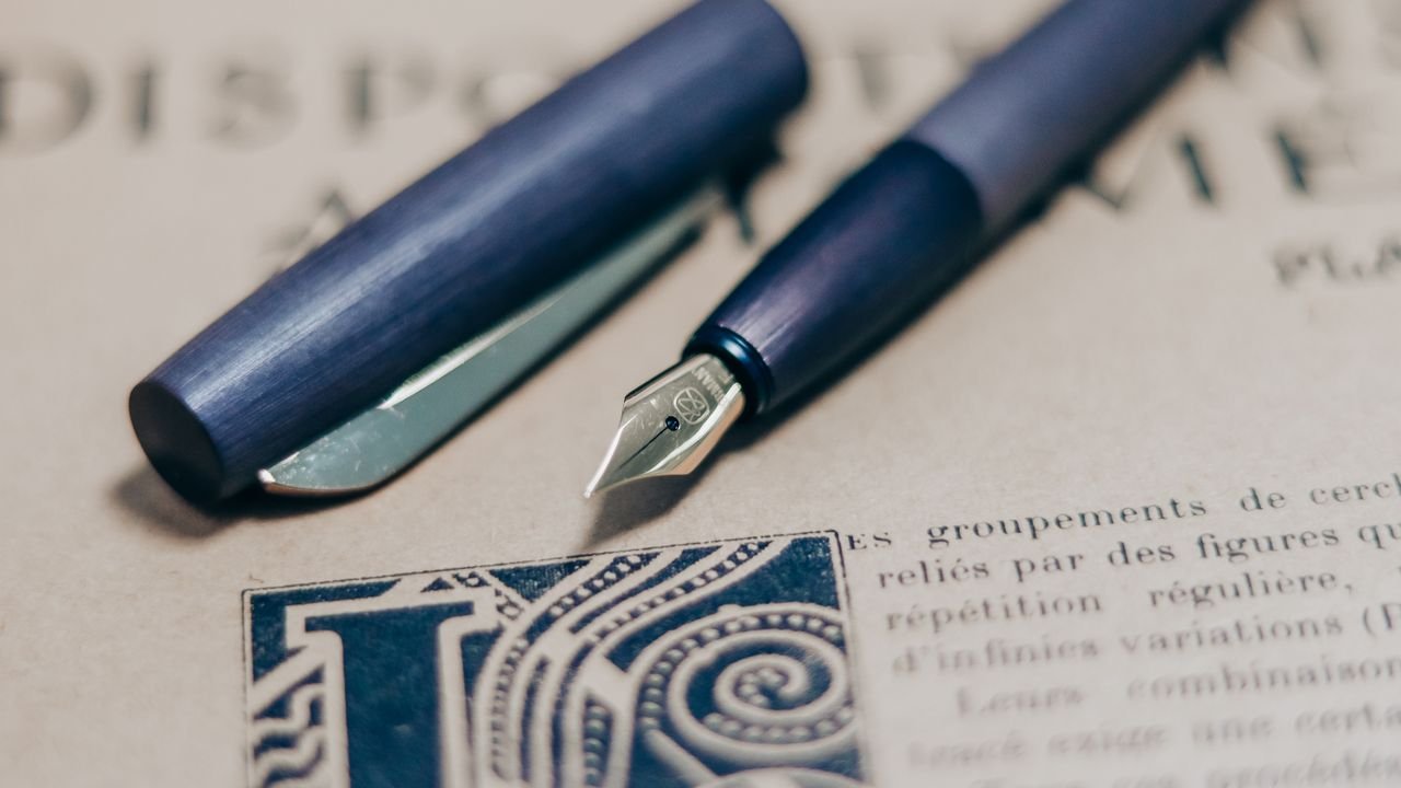 A close-up shot of a navy blue fountain pen on a vintage book page, showcasing elegant writing tools.